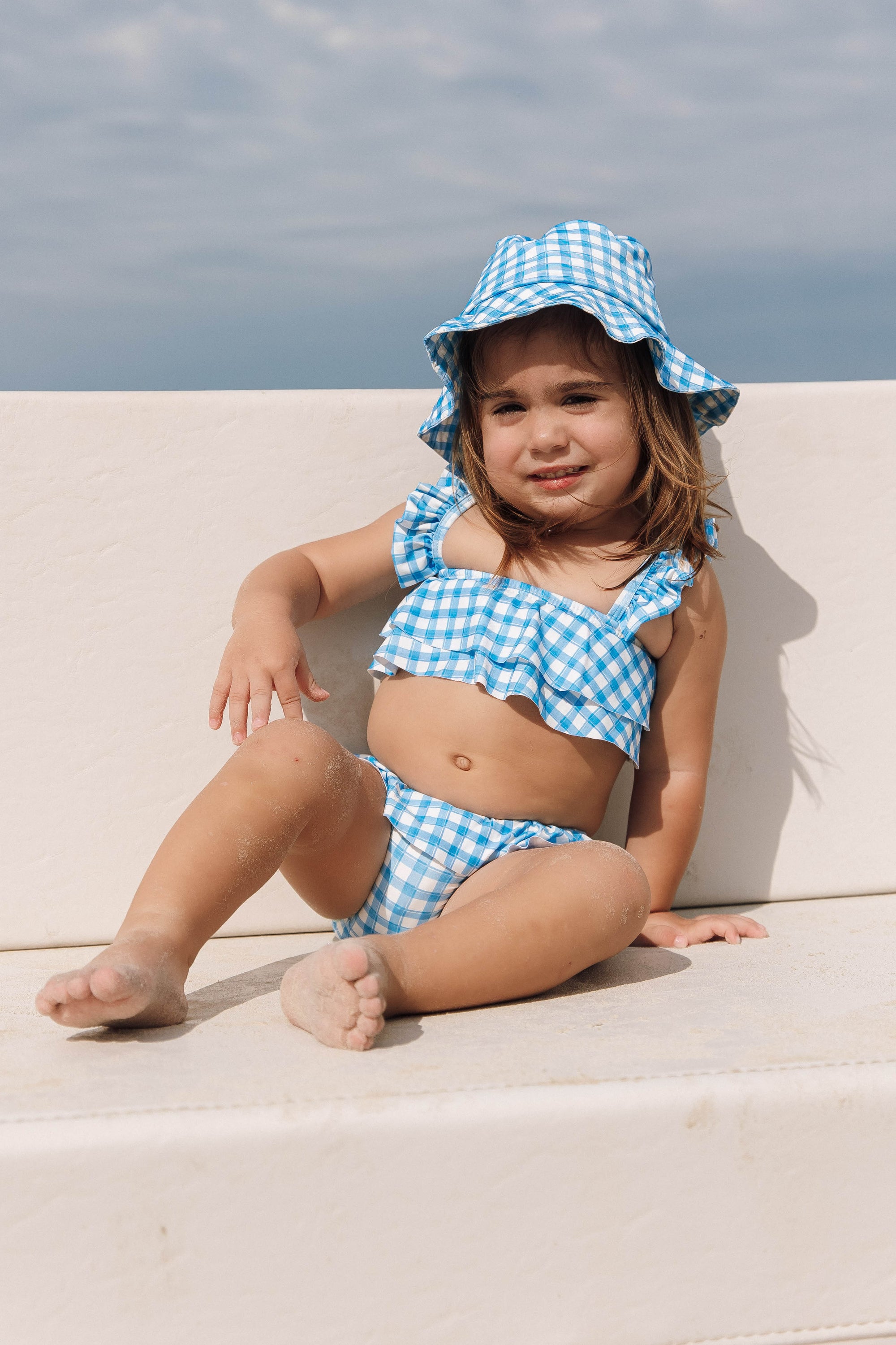 Bebe vestindo chapéu de praia infantil com protecao UV e biquíni de praia combinando com Vichy Azul da Lili Sampedro