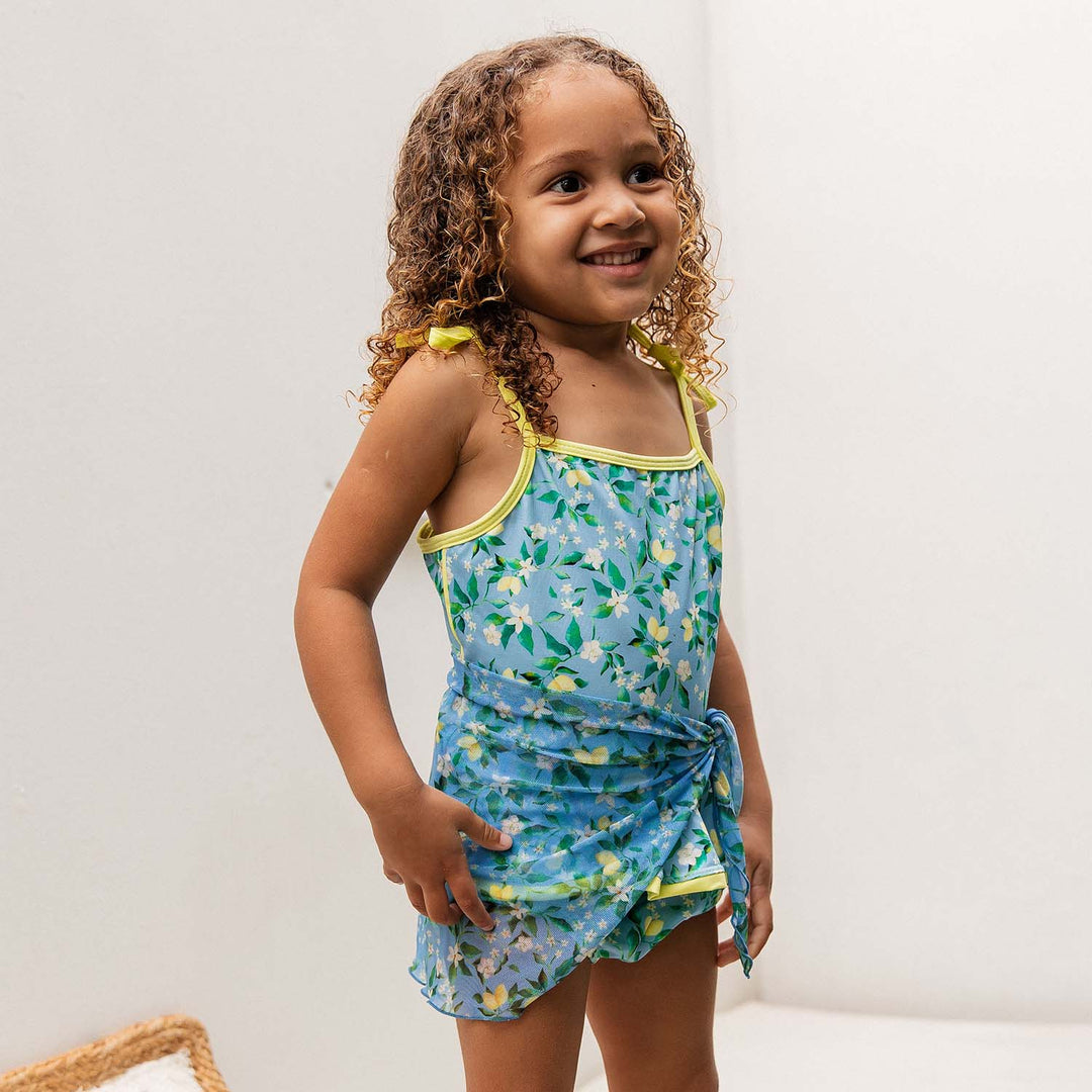 Modelo vestindo biquininho Liz com saídinha de praia Pareô infantil da Lili Sampedro, em estampa exclusiva Vichy Laranja