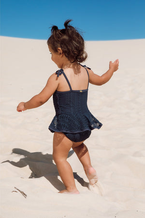 Menina na praia vestindo maio infantil de praia com babadinhos de renda azul marinho da Lili Sampedro