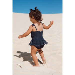 Menina na praia vestindo maio infantil de praia com babadinhos de renda azul marinho da Lili Sampedro