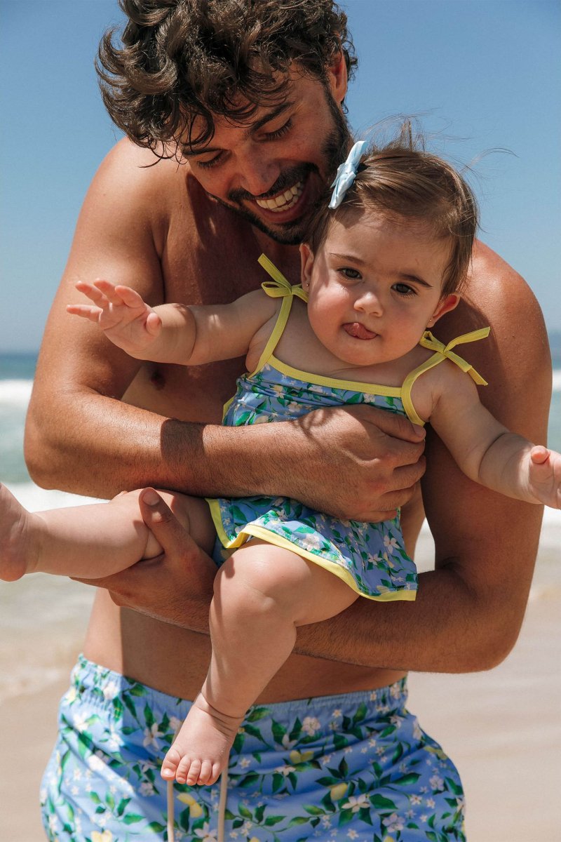 Pai e filha com look combinando na praia, de short e maiozinho na estampa Limoes da Lili Sampedro