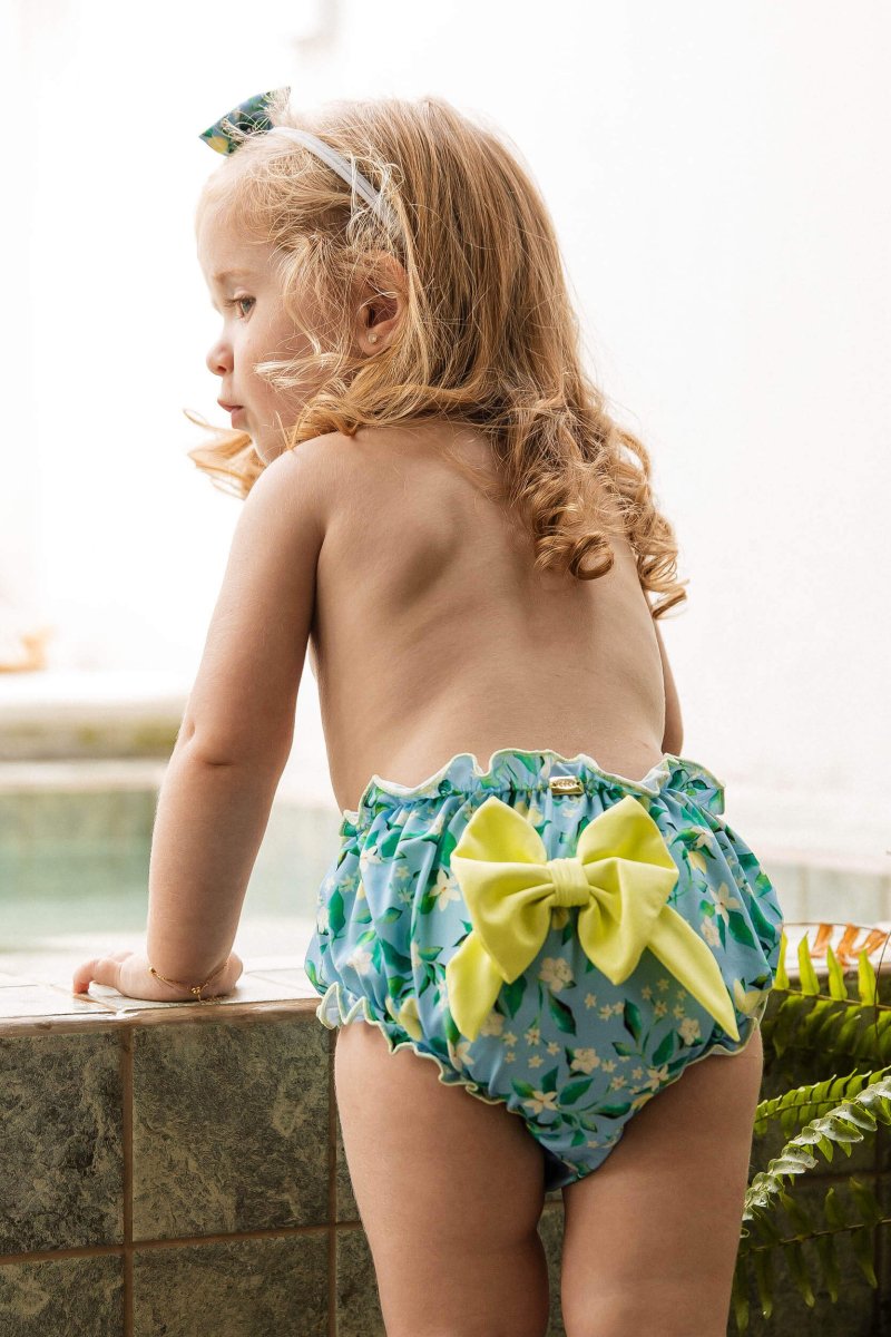 Modelo vestindo Tapa Fralda com proteção solar e lacinho de cabelo combinando na estampa Limões da Lili Sampedro