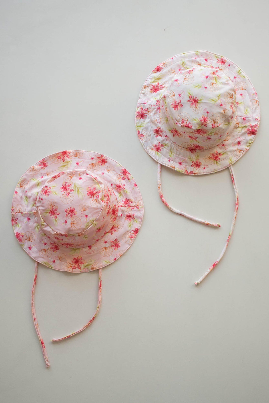 Chapéu de praia infantil com proteção UV feito em Lycra na estampa Hibiscos nas cores Off White e Rosa Claro