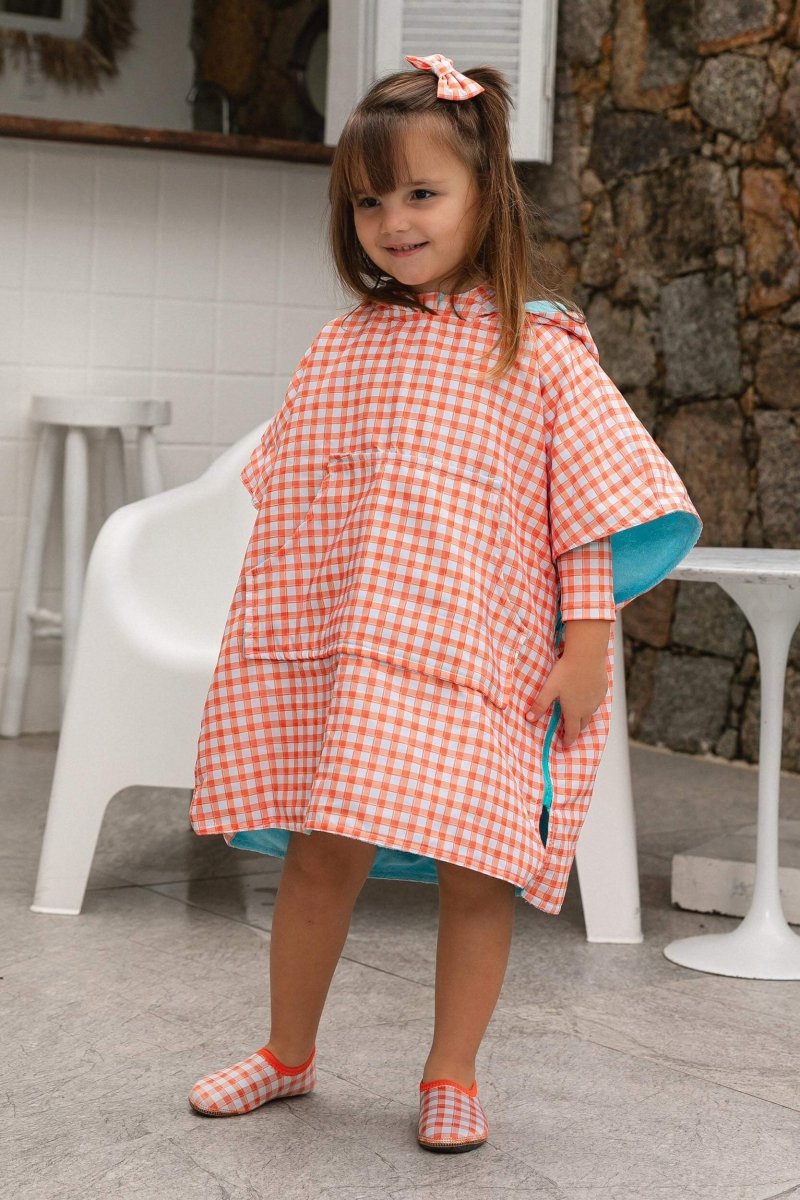 Modelo usando roupão infantil com tecido atoalhado e sapatinho de neoprene combinando na estampa Vichy Laranja