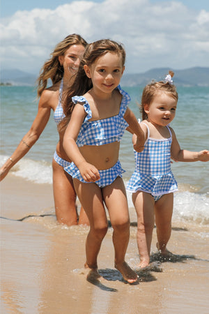 Meninas correndo na praia com look de praia combinando, uma de biquíni Vicky vestindo tamanho 6, e a outra com maiozinho olivia vestindo tamanho 2